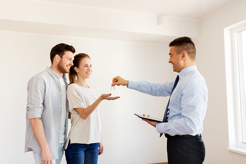 A mortgage broker hands a young couple the keys to their new home in Colorado Springs.