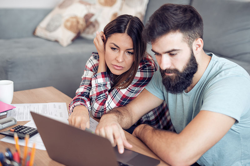 A young couple researching mortgage brokers in Colorado Springs on their computer.