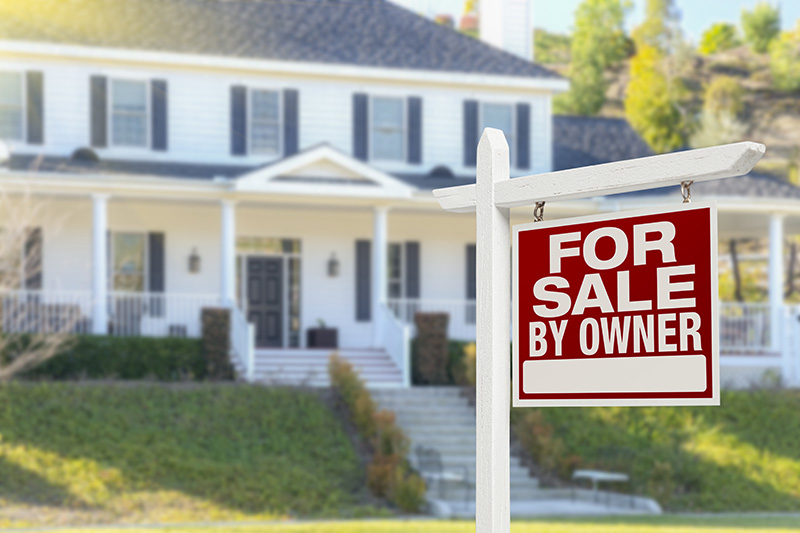 A sign outside of a beautiful home that's for sale by owner.