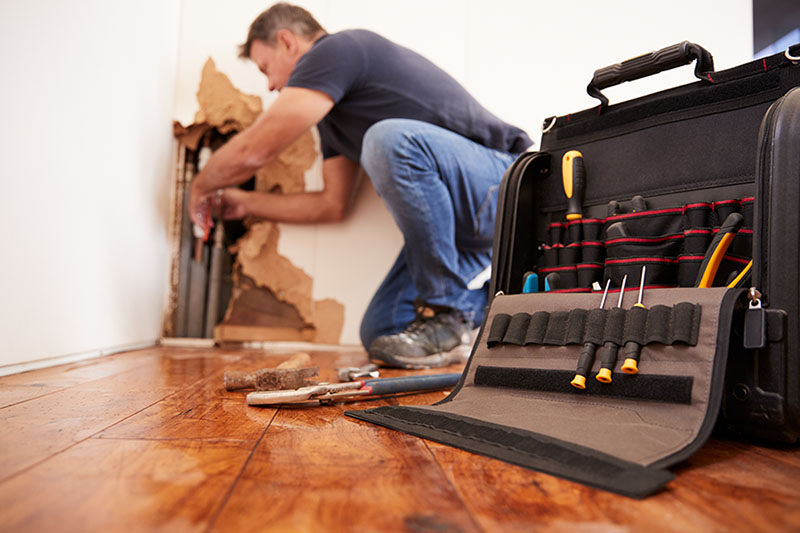 A plumber fixing a burst pipe in a new Colorado Springs home.