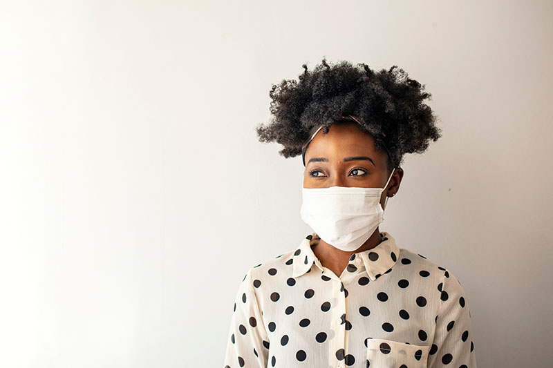 A woman wears a face mask while showing her home.