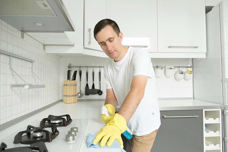 A man disinfects his kitchen during the COVID-19 pandemic.